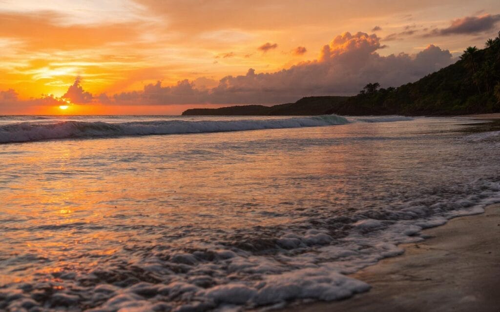 Un coucher de soleil sur la plage de Hendaye, avec des couleurs vives se reflétant sur l'eau et des vagues douces qui viennent lécher le rivage, créant une atmosphère chaleureuse et tranquille.